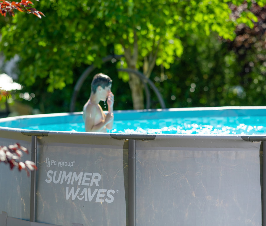 Junge steht im Wasser im Summer Waves Elite-Frame-Pool.