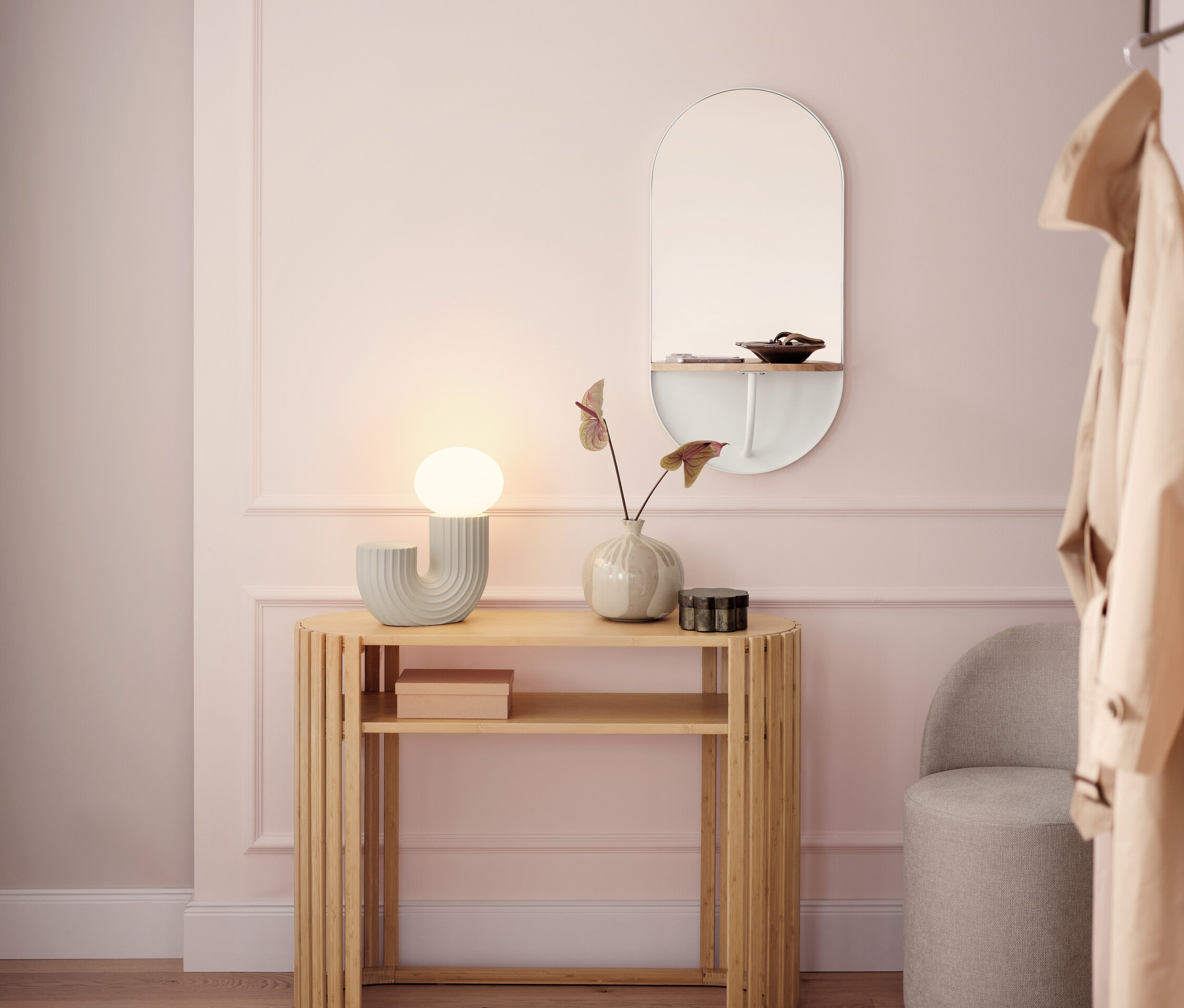 Heller Flur mit einem hölzernen Konsolentisch, einer Lampe, einem Spiegel und einem grauen Hocker.