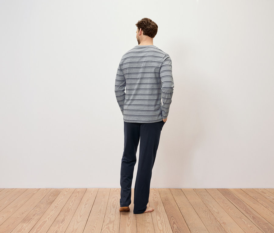 Ein Mann mit dem Rücken zur Kamera trägt ein gestreiftes Langarmshirt und dunkelblaue Hosen.