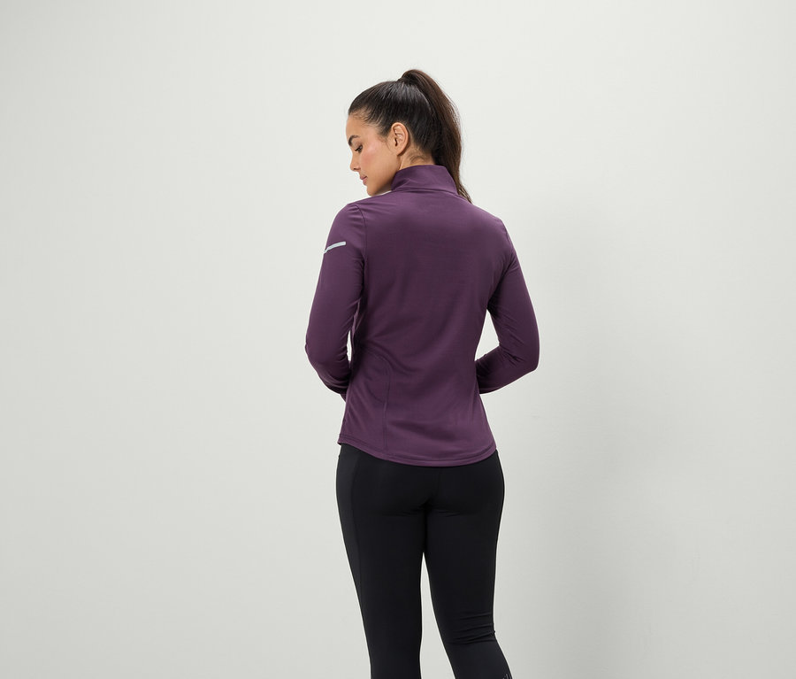 Rückansicht einer Frau mit Pferdeschwanz in einer dunkelvioletten Jacke und schwarzen Leggings.