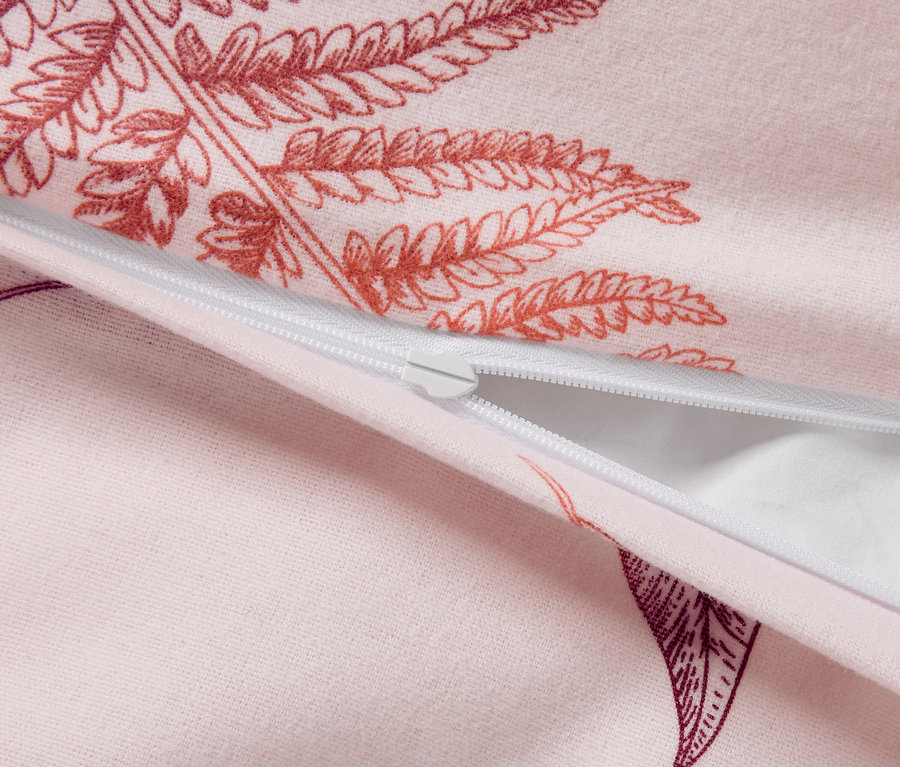 Detailaufnahme eines rosa Bettbezugs mit Farnmuster und weißem Reißverschluss.