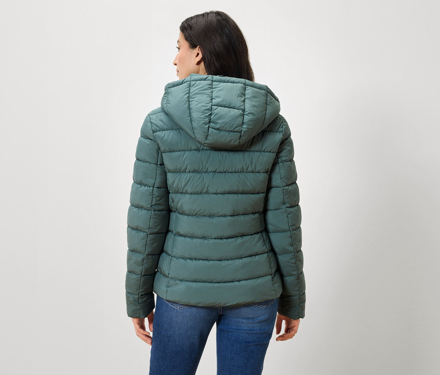 Frau mit dem Rücken zur Kamera trägt eine grüne Daunenjacke und Jeans.