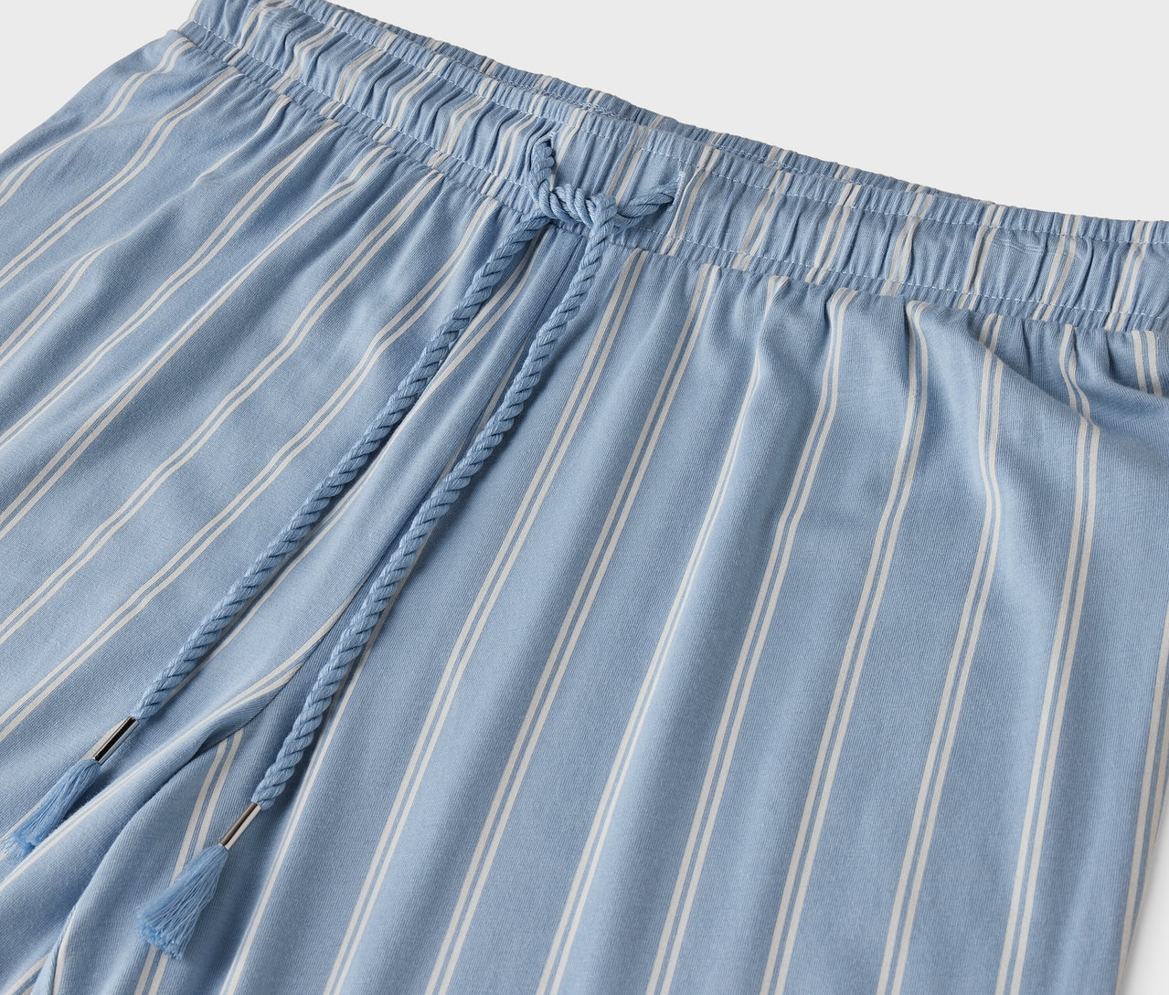 Detail einer blau gestreiften Hose mit Kordelzug in der Taille.