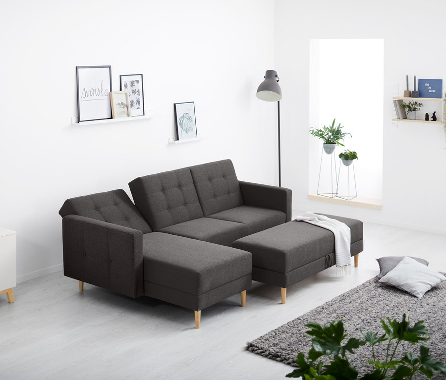 Im Wohnzimmer steht ein Federkern-Eckschlafsofa mit Stauraumbank.