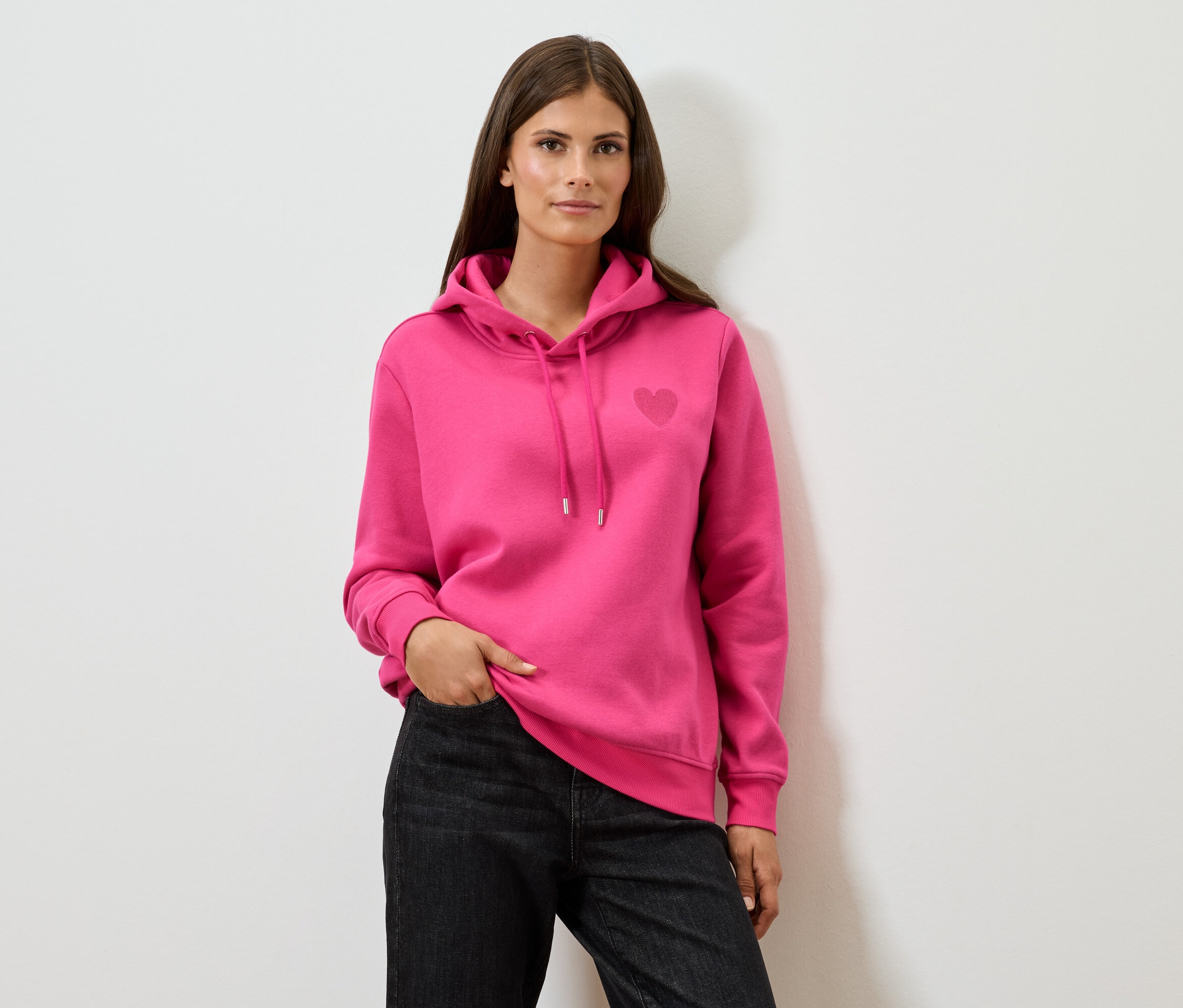 Frau trägt einen pinken Hoodie und schwarze Jeans.