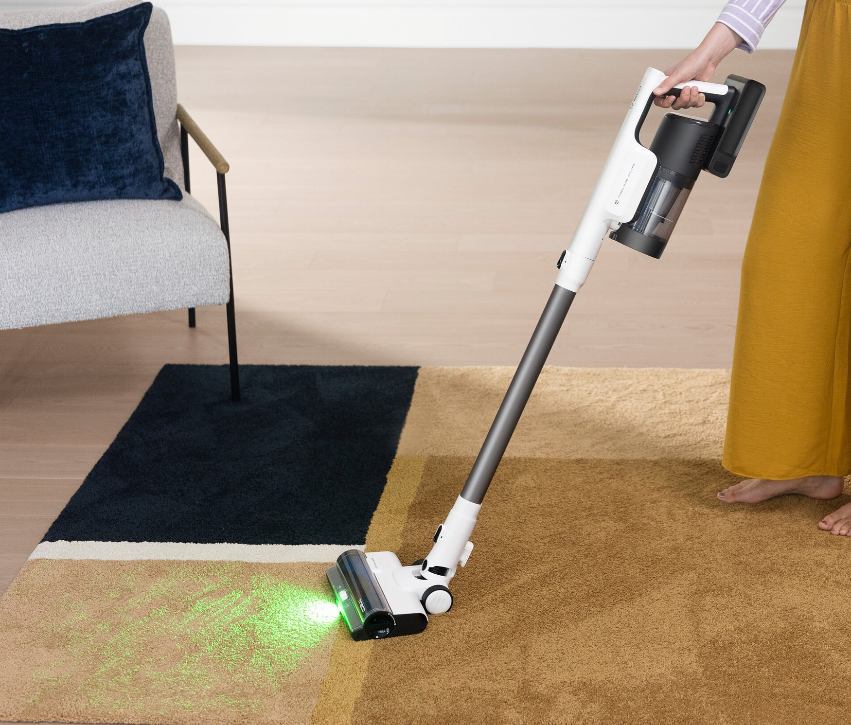 Frau saugt mit Tineco Akku-Staubsauger Pure One Station 5 einen Teppich.