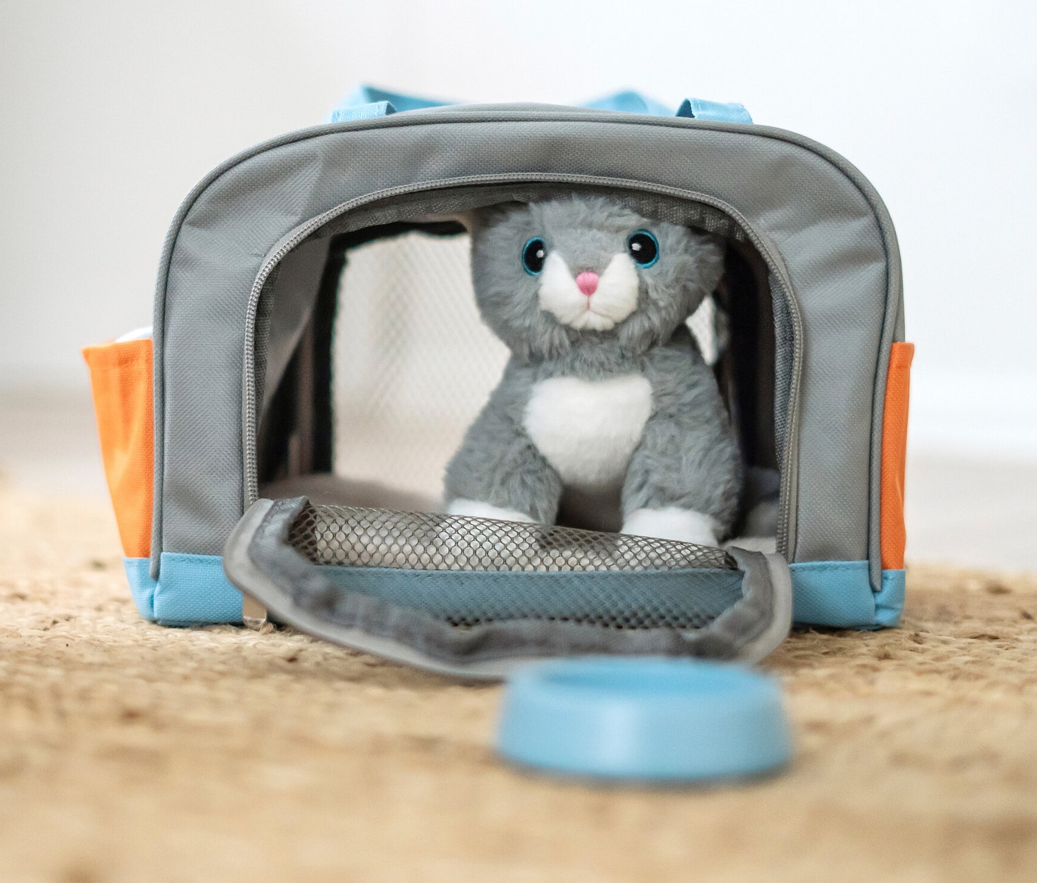 Kind spielt mit small foot Katze mit Tasche und Pflege-Set auf einem Jute-Teppich.