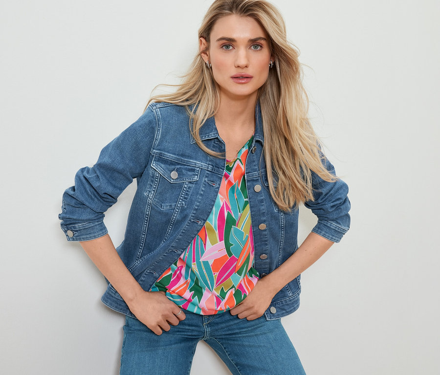 Frau posiert in Jeansjacke, überschnittenem Blusenshirt mit Alloverprint und Straight Jeans – Fit »Kira«.