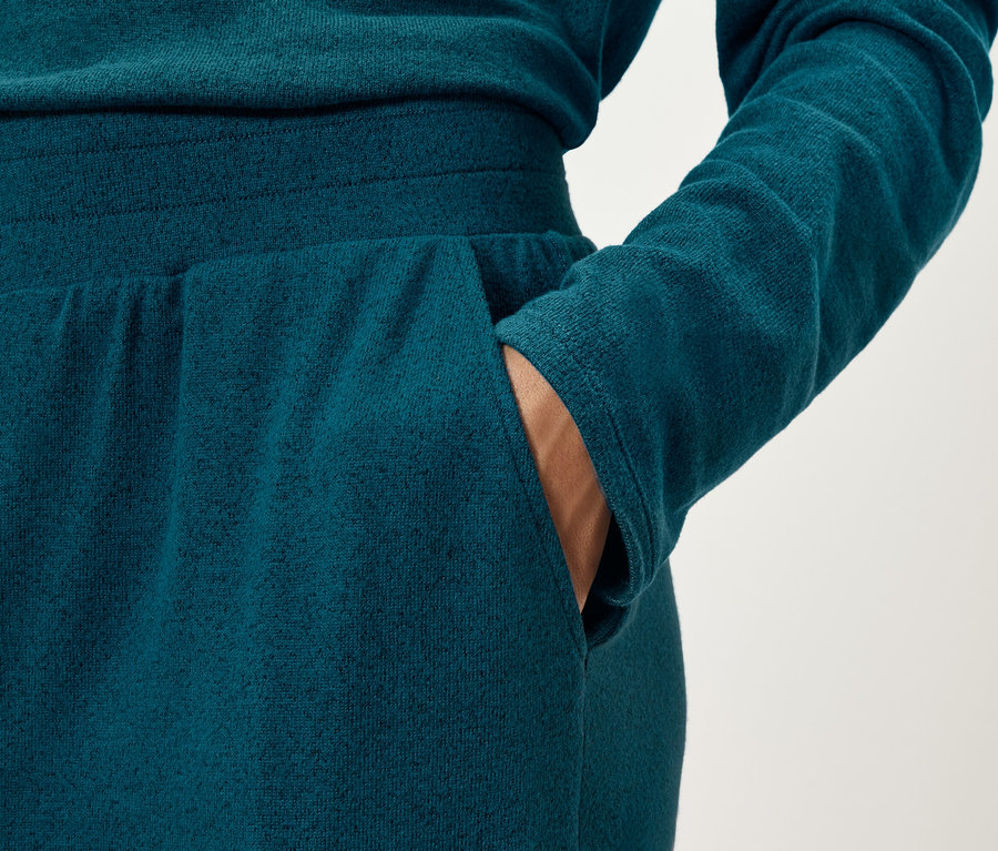 Detailaufnahme einer Frau, die eine marineblaue Jogginghose trägt und ihre Hand in die Hosentasche steckt.