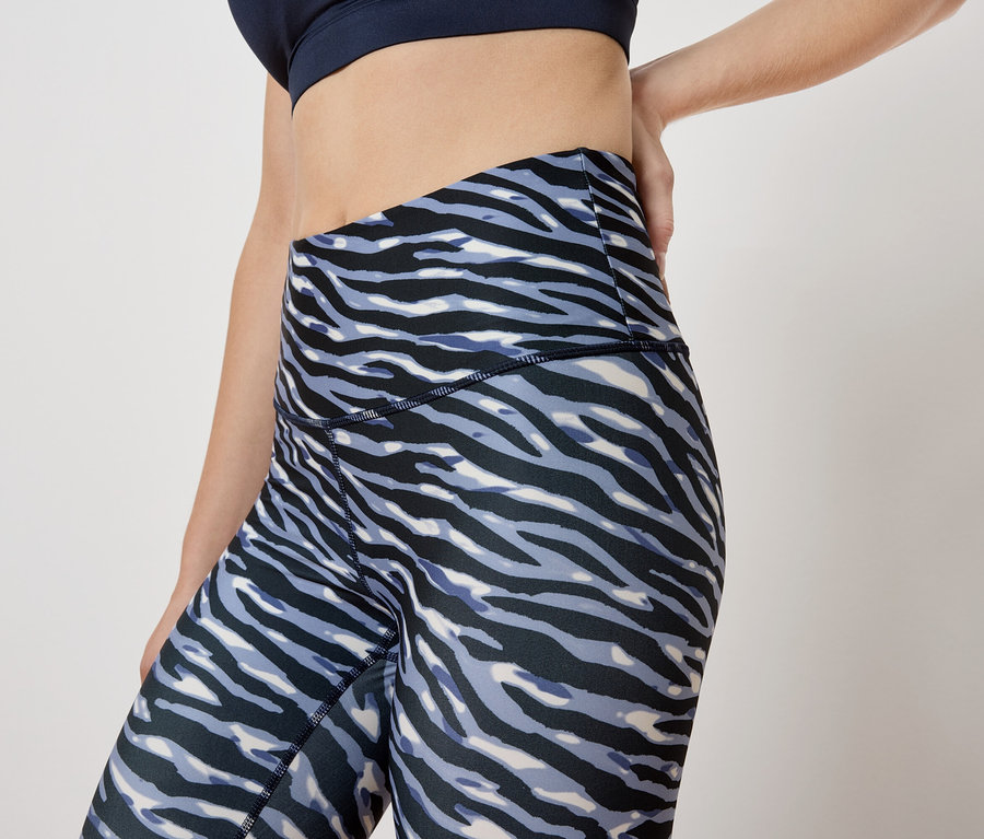 Frau posiert in Leggings mit Tiermuster und Sport-BH.