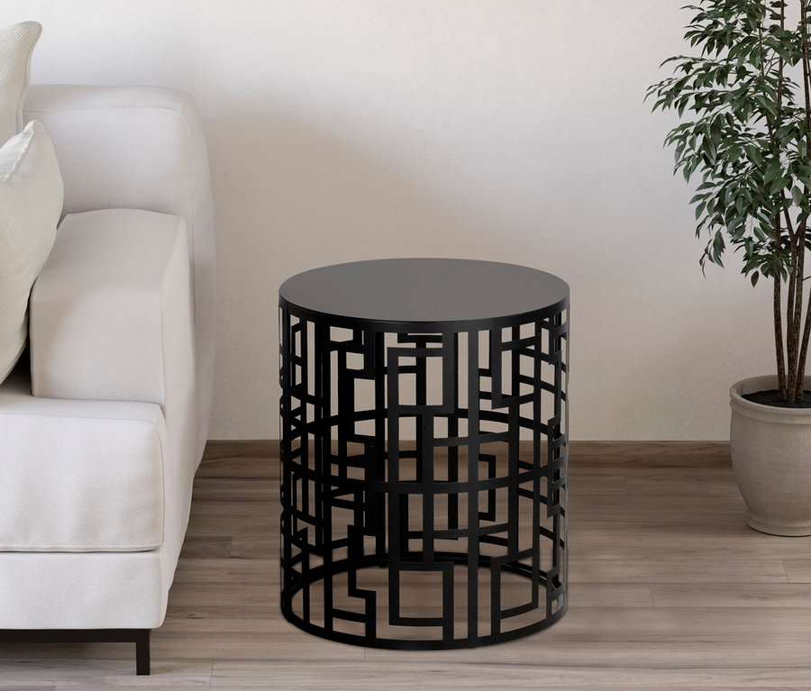 Schwarzer Beistelltisch mit geometrischem Muster neben einem weißen Sofa und einer Zimmerpflanze.