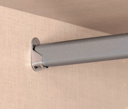 Nahaufnahme einer silbernen Kleiderstange, die an einer beigen Wand befestigt ist.