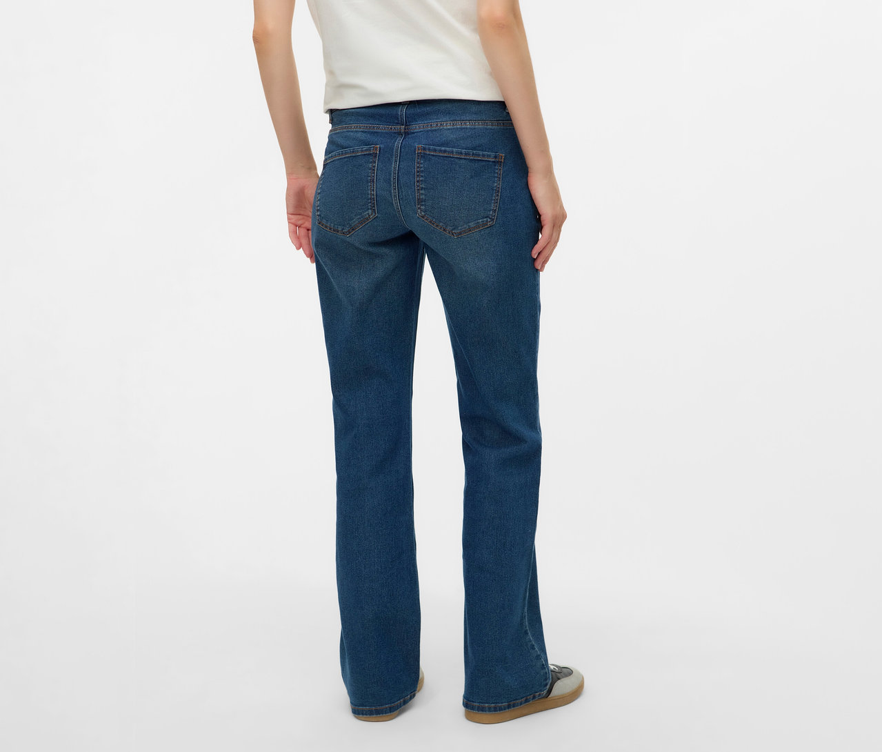 Rückansicht einer Frau mit weißem T-Shirt und MAMALICIOUS Flared Jeans »MLEDINA« vor einem weißen Hintergrund.