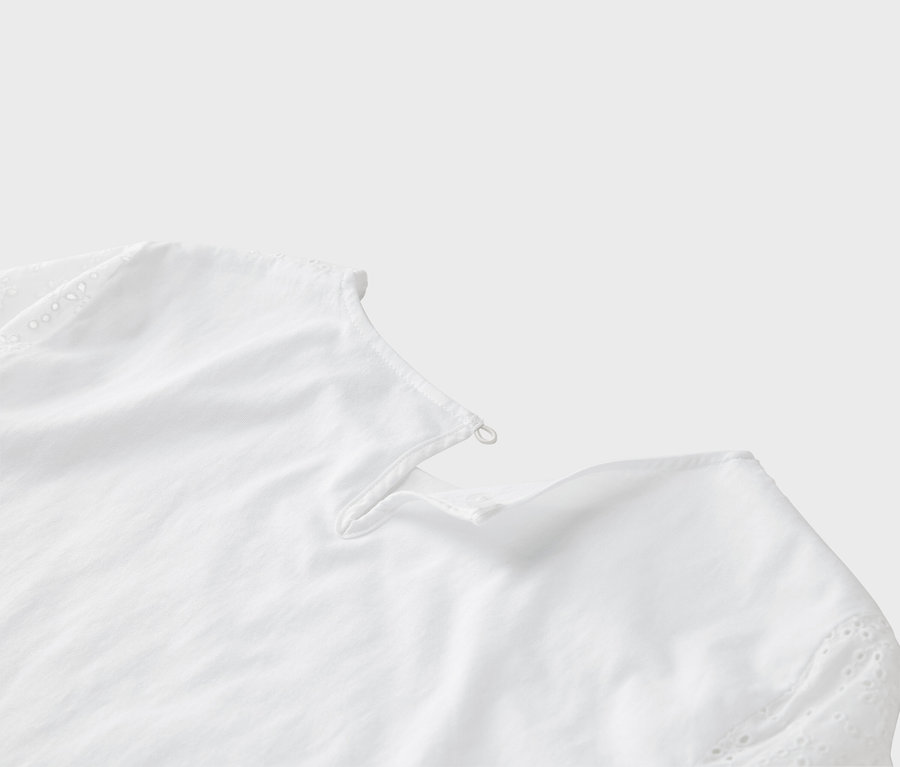 Detailansicht einer weißen Bluse mit Lochstickerei am Ärmel.