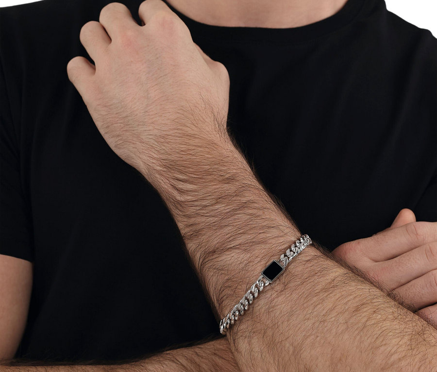 Nahaufnahme eines Mannes, der ein Amor Unisex-Armschmuck mit Anhänger trägt.
