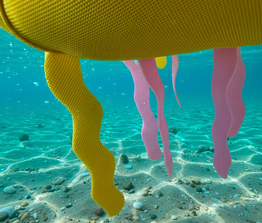 Gelbe und rosa Dekoration unter Wasser, möglicherweise Teil einer Installation oder eines Kunstwerks.