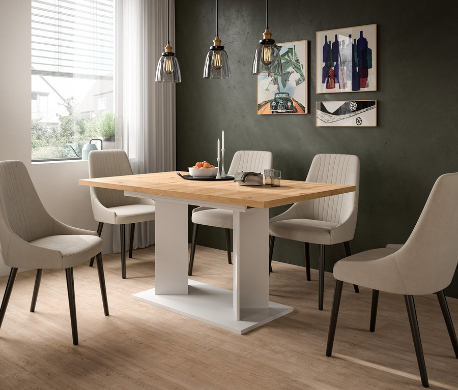 Ein modernes Esszimmer mit einem Holztisch und sechs beigen Stühlen. Auf dem Tisch stehen eine Obstschale, Kerzen, Teller und Gläser. Eine dunkelgrüne Wand mit drei Bildern und drei Pendelleuchten ist im Hintergrund zu sehen.
