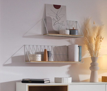 Frau sitzt im Wohnzimmer neben einem weißen Sideboard »Eklund« mit Schubladen und Tür.