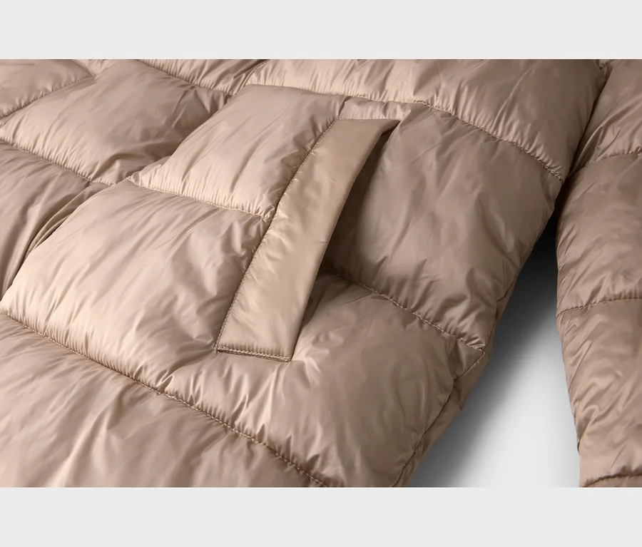 Nahaufnahme einer beigen Steppjacke mit sichtbarer Taschenklappe.