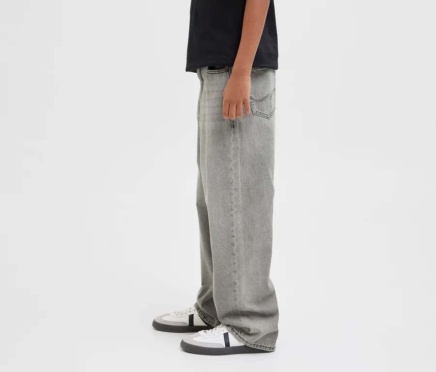 Person trägt ein schwarzes T-Shirt, graue Jack&Jones JJOrginial Alex Jeans und weiße und graue Sneaker.