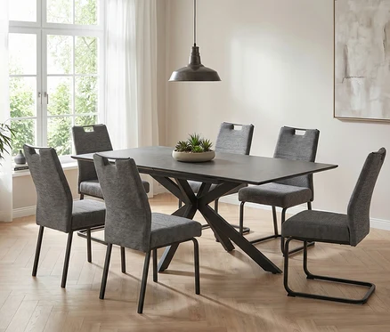 Ein Esszimmer mit einem Hela Auszugstisch »Fenja II« mit dunkler Platte und sechs grauen Stühlen. Eine Hängeleuchte und eine Pflanze schmücken den Raum.