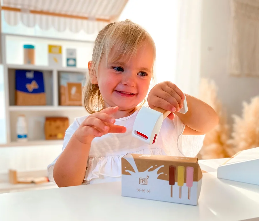 Lächelndes blondes Mädchen spielt mit Spielzeug im small foot Kaufladen kompakt »fresh«.