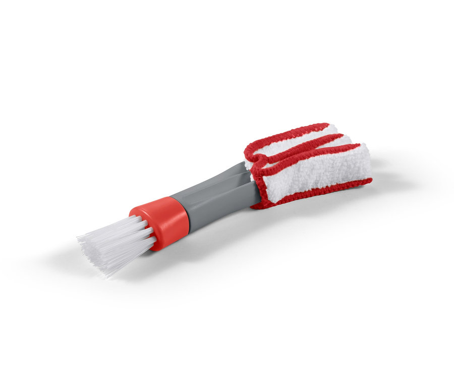 Eine 2-in-1-Reinigungsbürste mit weißen Borsten, einem grauen Griff und einem rot-weißen Lamellenreinigungsaufsatz.