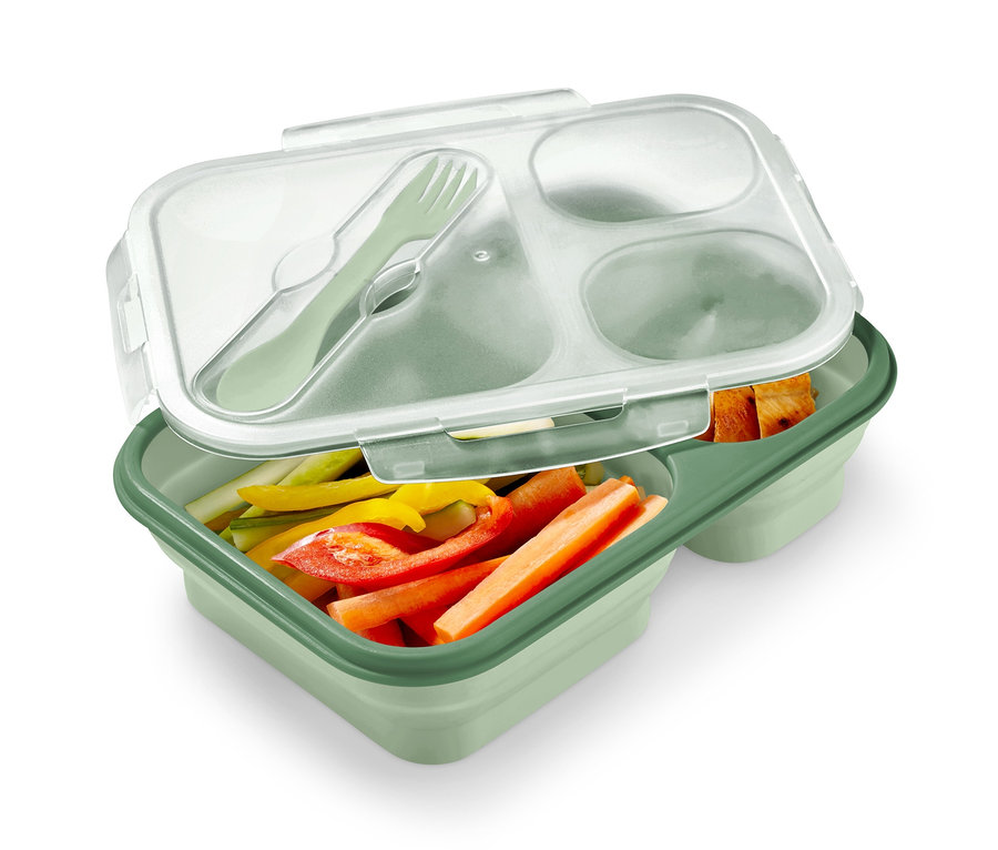 Eine grüne, faltbare Lunchbox gefüllt mit geschnittenem Gemüse und Besteck.