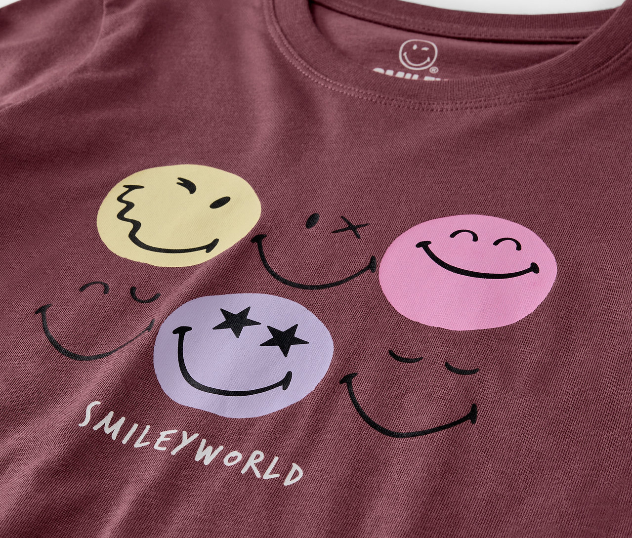 Detailansicht eines violetten Kinder-Pyjamas von SMILEYWORLD® mit Gesichtern.