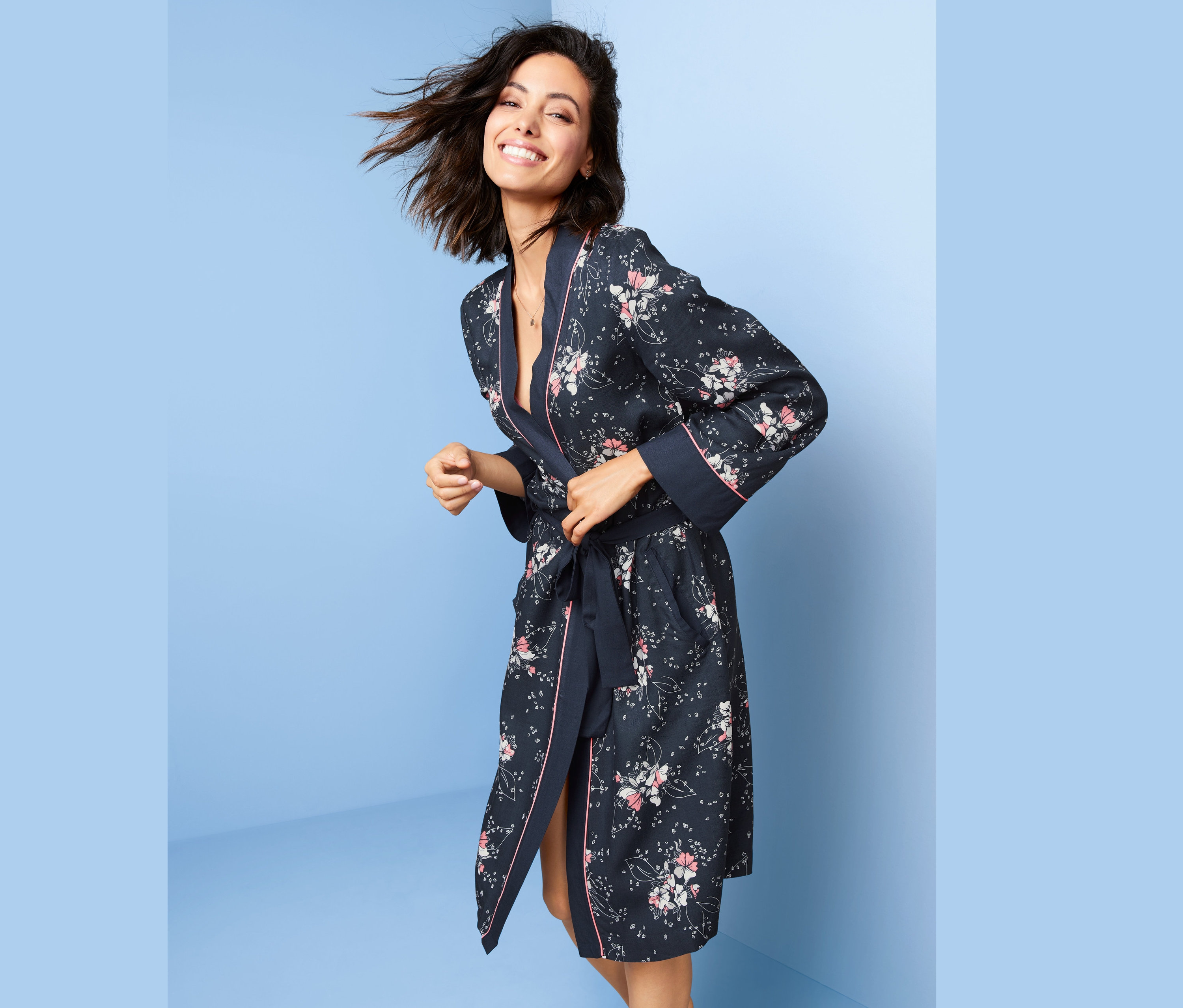 Lächelnde Frau bindet ihren geblümten Morgenmantel