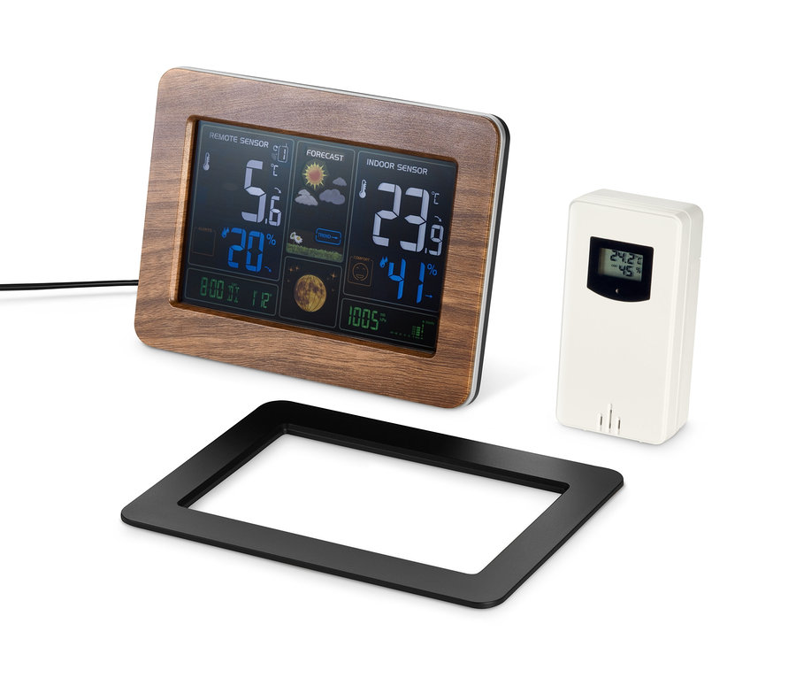 Eine Funk-Wetterstation mit LC-Farbdisplay und Außensensor steht auf einem Tisch, zusammen mit einer schwarzen Halterung.