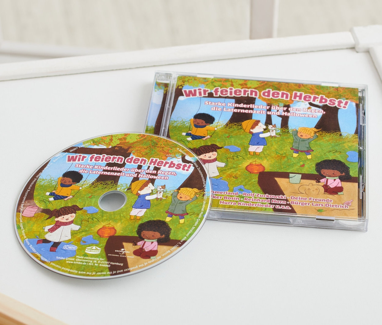 Auf einem weißen Tisch liegen eine CD »Wir feiern den Herbst!« und ein Holzspielzeug.