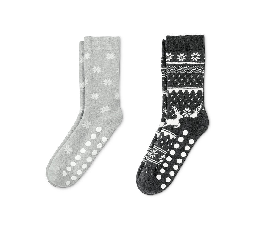 Zwei Paar Antirutsch-Socken: Ein Paar ist grau mit Schneeflockenmuster, das andere dunkelgrau mit Rentier-Motiv.