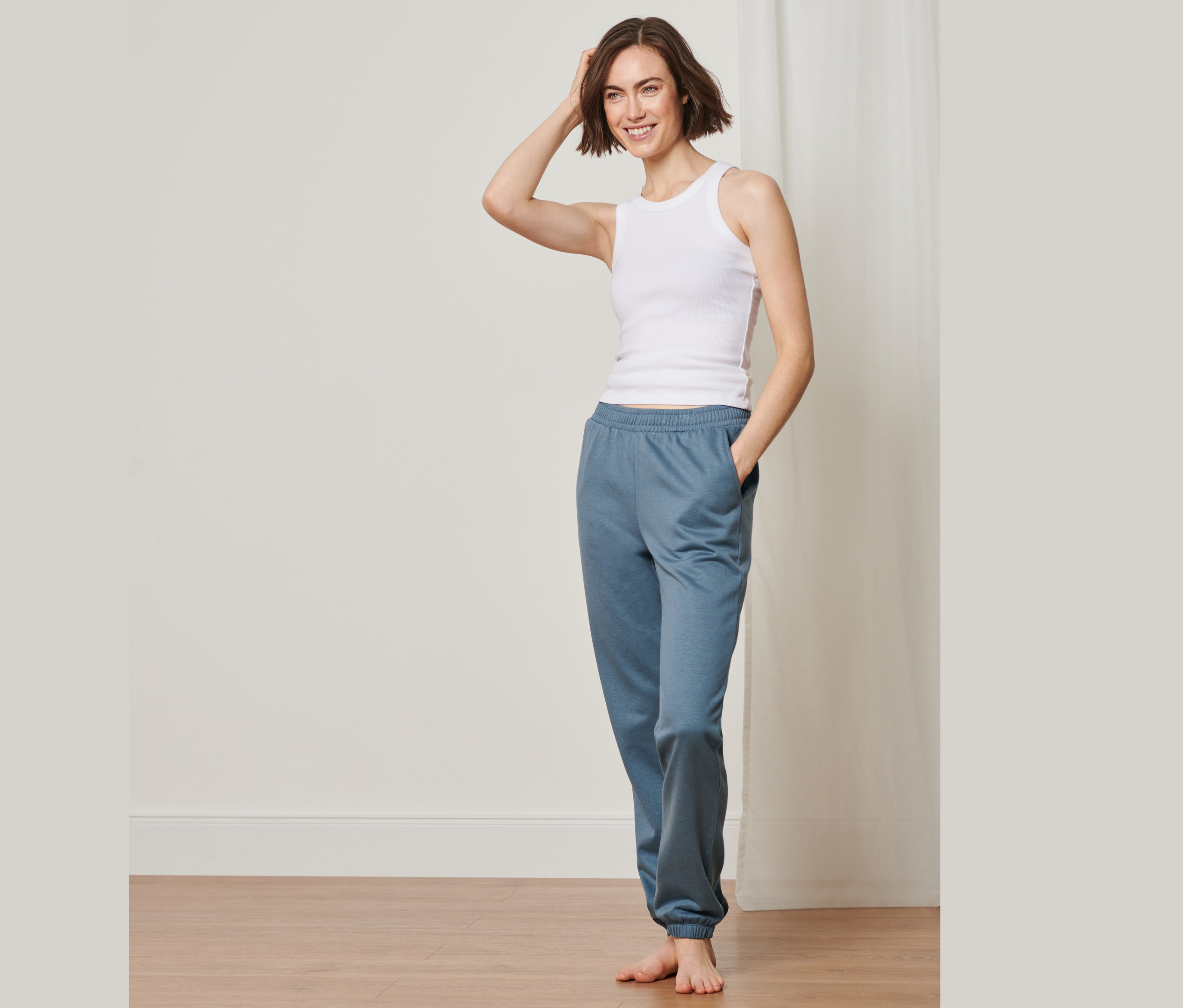 Frau posiert in einem Tanktop und einer Loungewear-Hose.
