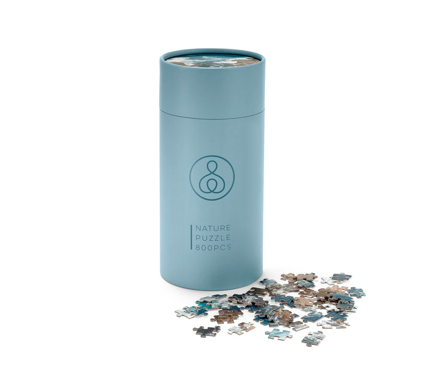 Eine blaue Puzzle »Ozean«-Tube mit ein paar Puzzleteilen daneben.