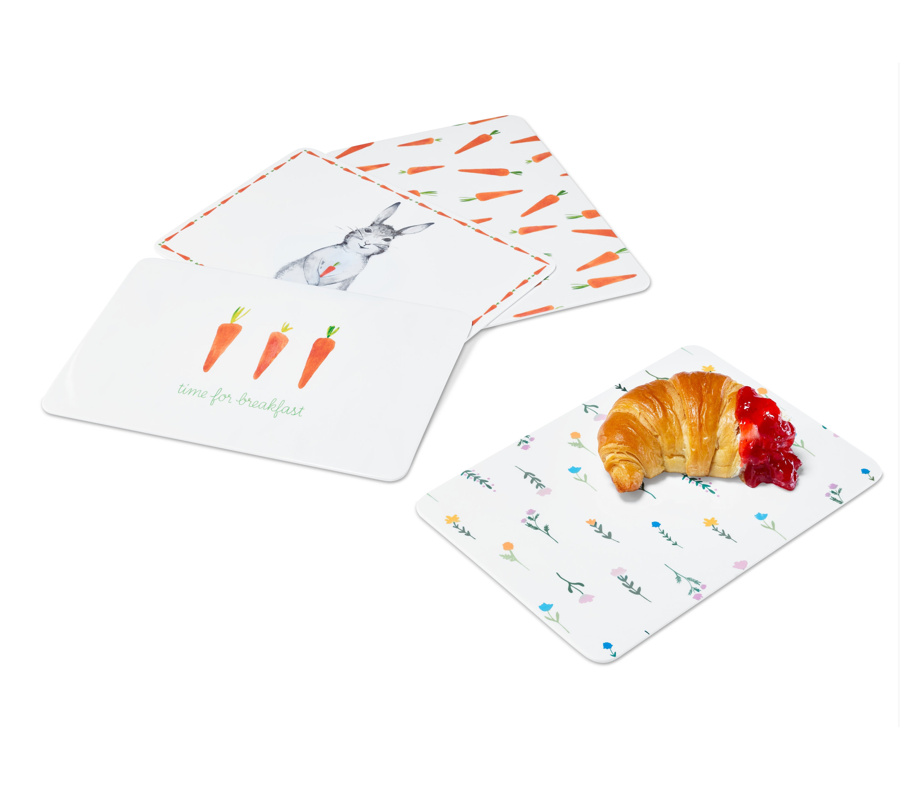 Vier Schneidebretter mit unterschiedlichen Ostermotiven und ein Croissant mit Marmelade.