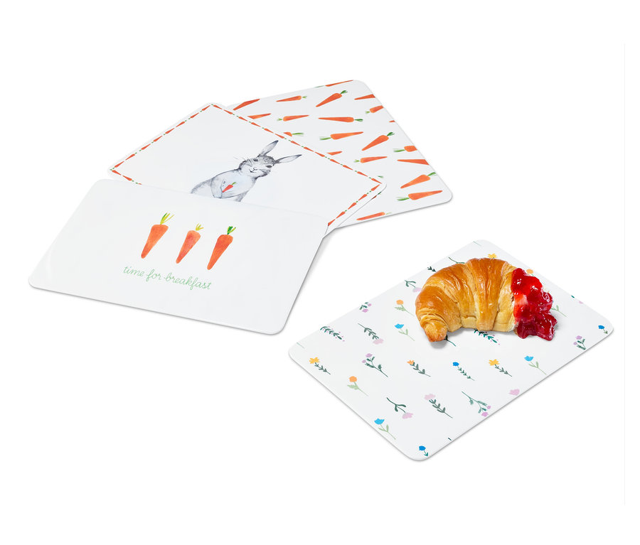 Vier Schneidebretter mit unterschiedlichen Ostermotiven und ein Croissant mit Marmelade.