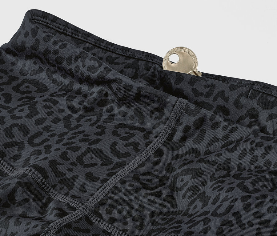 Detailansicht einer grau-schwarzen Sporttight mit Leopardenmuster und einem Schlüssel in der Tasche.