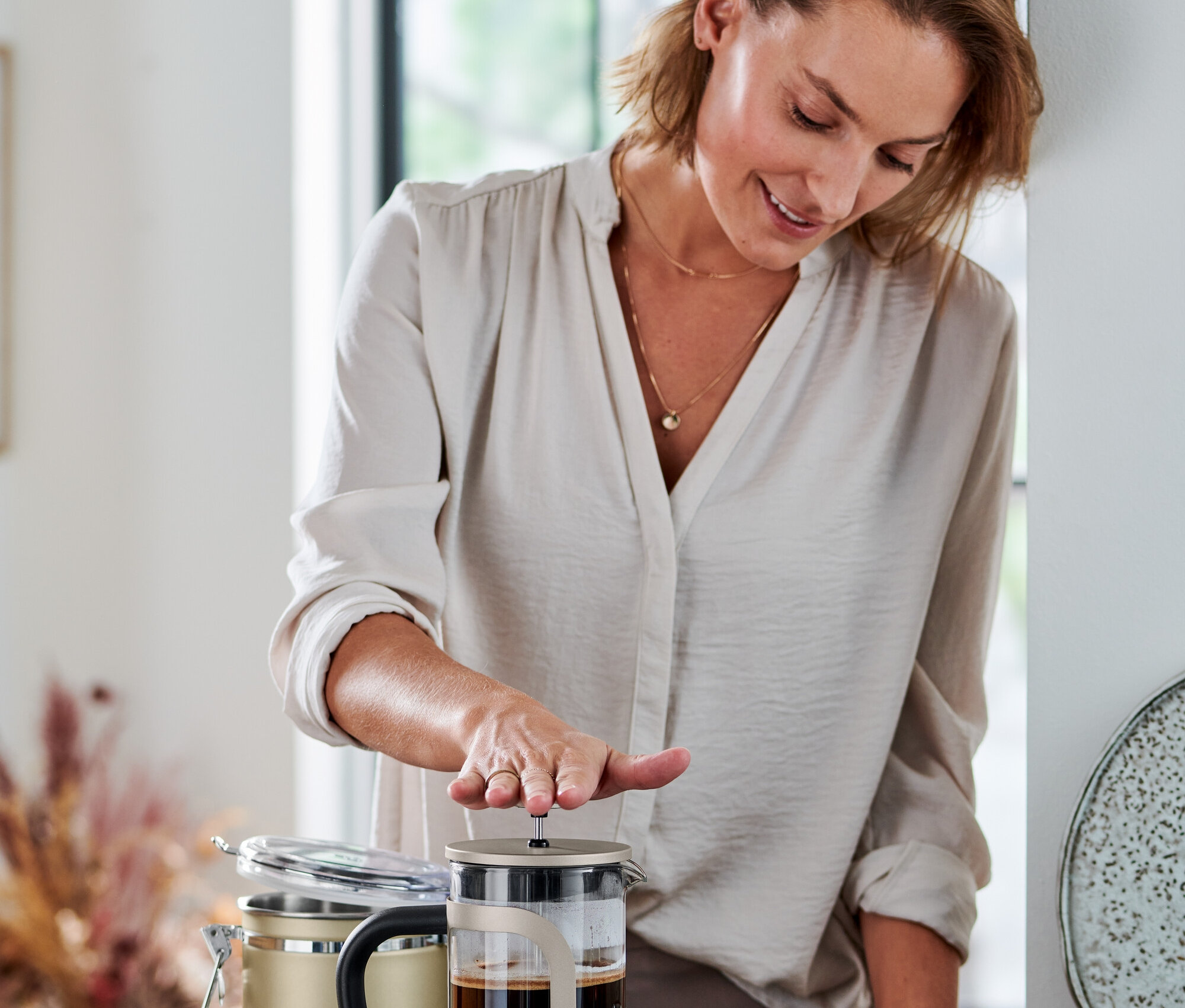 Frau drückt Siebstempelkanne 800 ml, 6 Tassen, champagner.