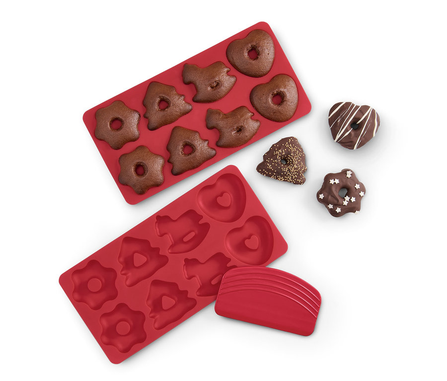 Zwei rote Mini-Lebkuchen-Backmatten, eine davon mit Lebkuchenteig gefüllt, und vier fertige Lebkuchen.