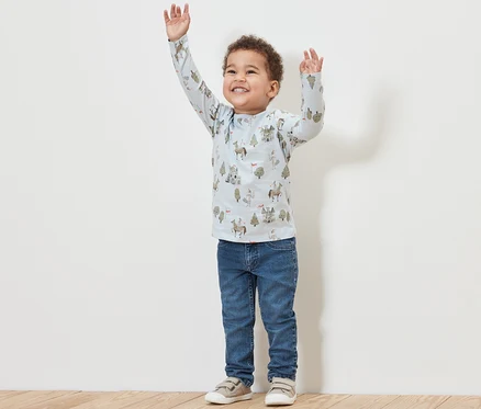Junge mit erhobenen Armen trägt Kinder-Jeans – Fit »Jonas« und ein bedrucktes Shirt.