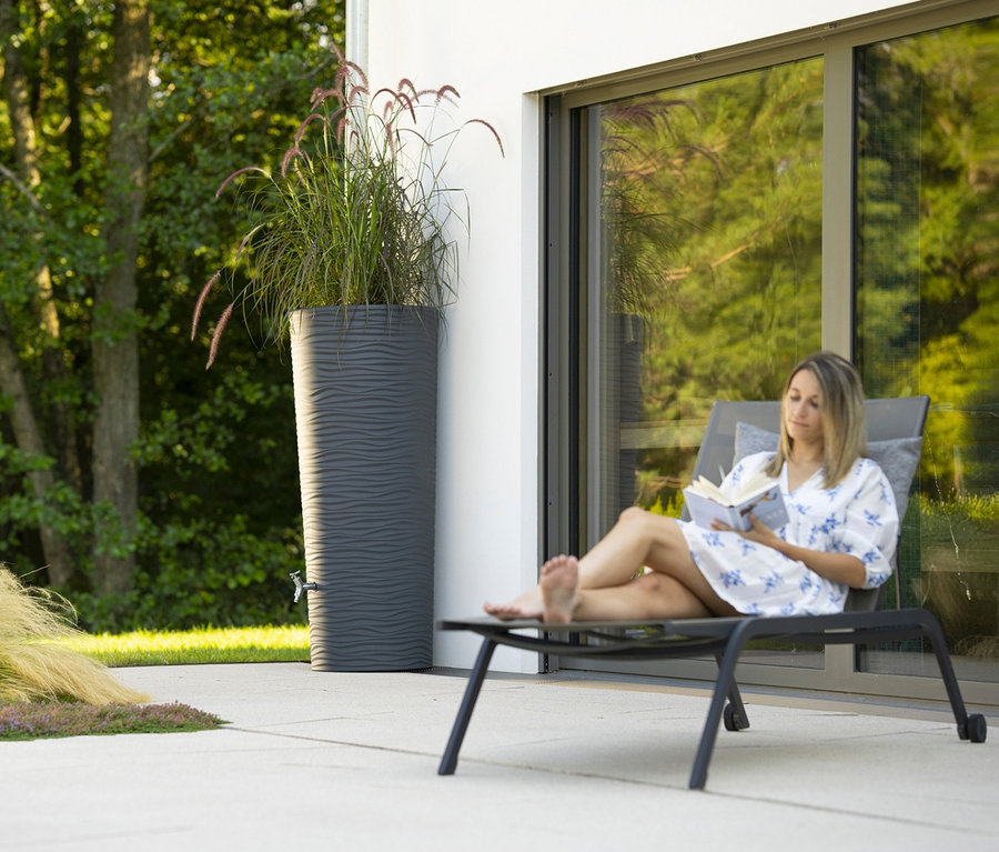 Frau liest Buch auf Liege neben Garantia 2-in-1-Regentonne-Komplett-Set, ca. 350 l, graphit-grau.