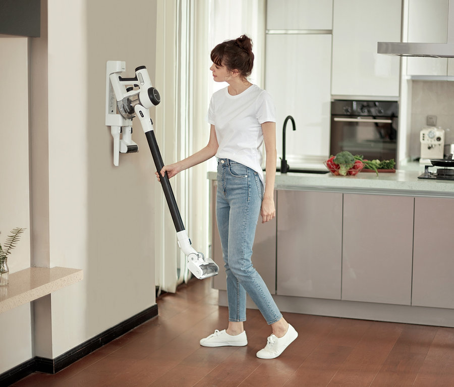 Frau nimmt Tineco Pure One x Essentials Akkusauger von der Wandhalterung.
