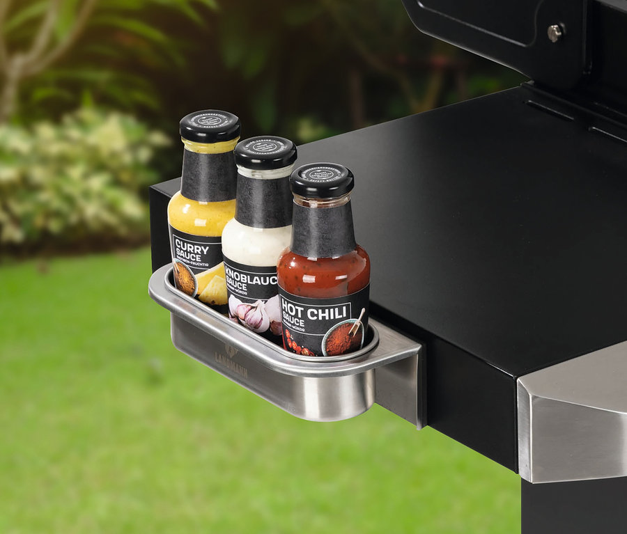 Drei Saucenflaschen in einem Landmann magnetisches Zubehör Metallhalter, der an der Seite eines Grills befestigt ist.