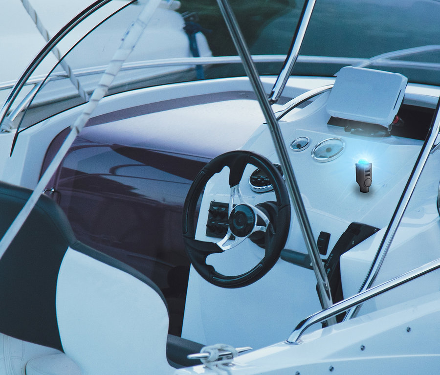Innenansicht eines Bootes mit Steuerrad und Armaturenbrett, darauf ein mobiler Mini-Alarm mit Bewegungsmelder.