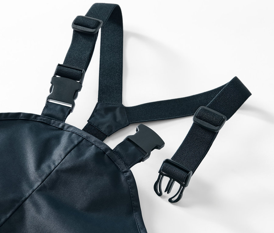 Detailansicht einer Kinder-Regenhose mit schwarzen, elastischen Hosenträgern und Kunststoffschnallen auf weißem Hintergrund.