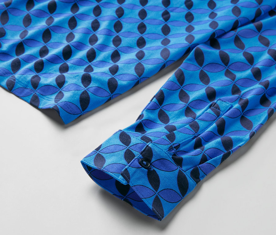 Detailansicht eines blau gemusterten Blusenshirts mit Knopfleiste am Ärmel.