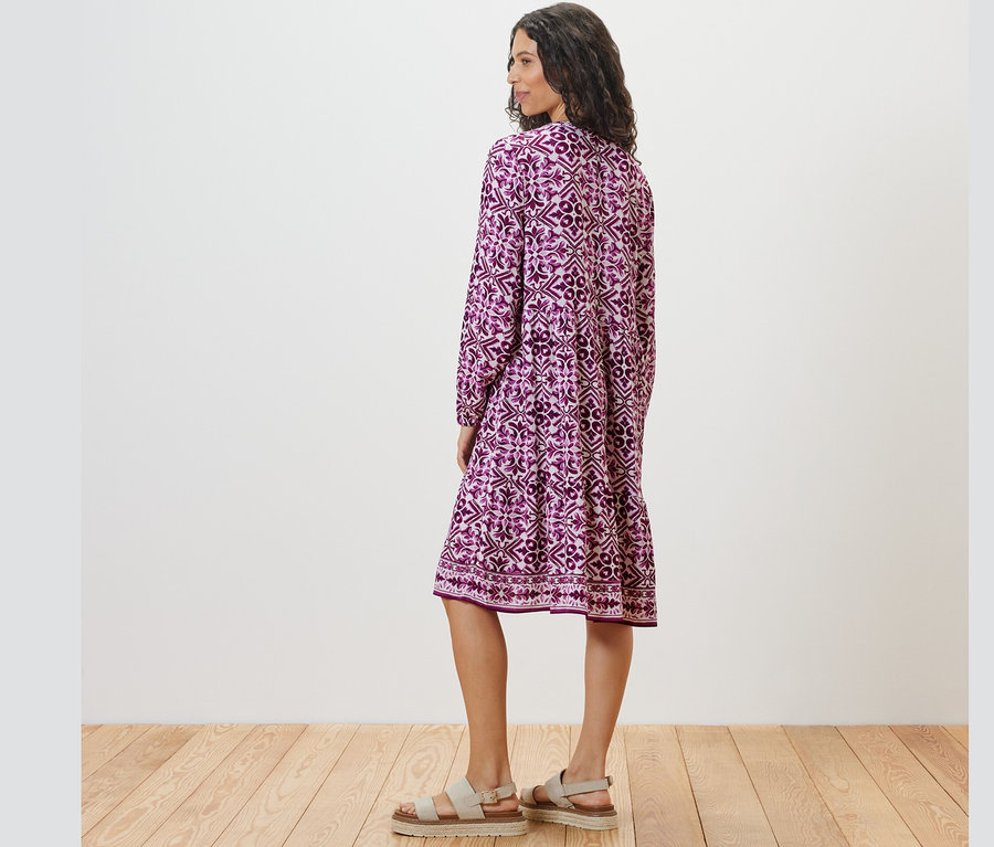 Frau posiert von hinten in einem bedruckten Webkleid.