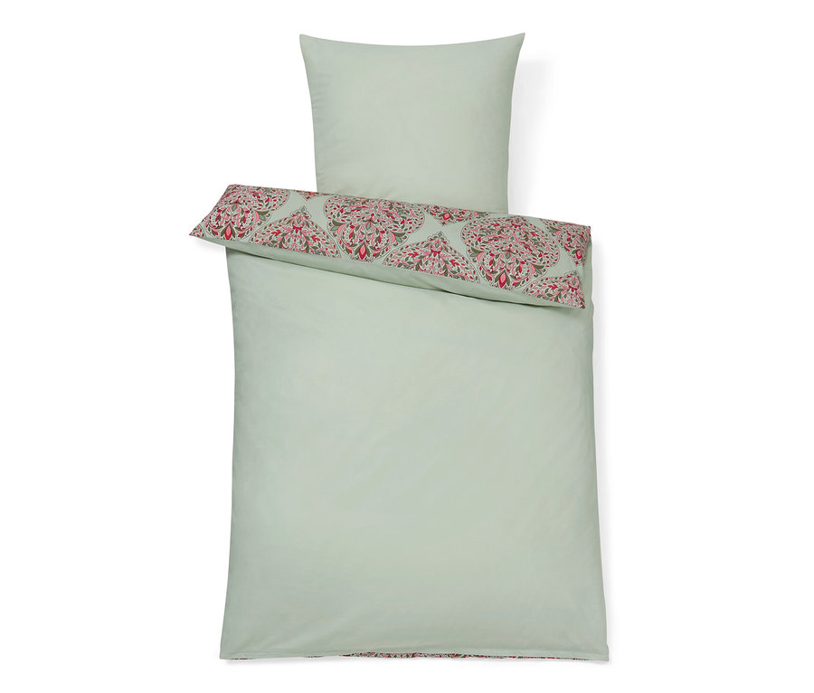 Hellgrüne Baumwollbettwäsche mit Blumenmuster auf dem Kissen und am Rand der Bettdecke.