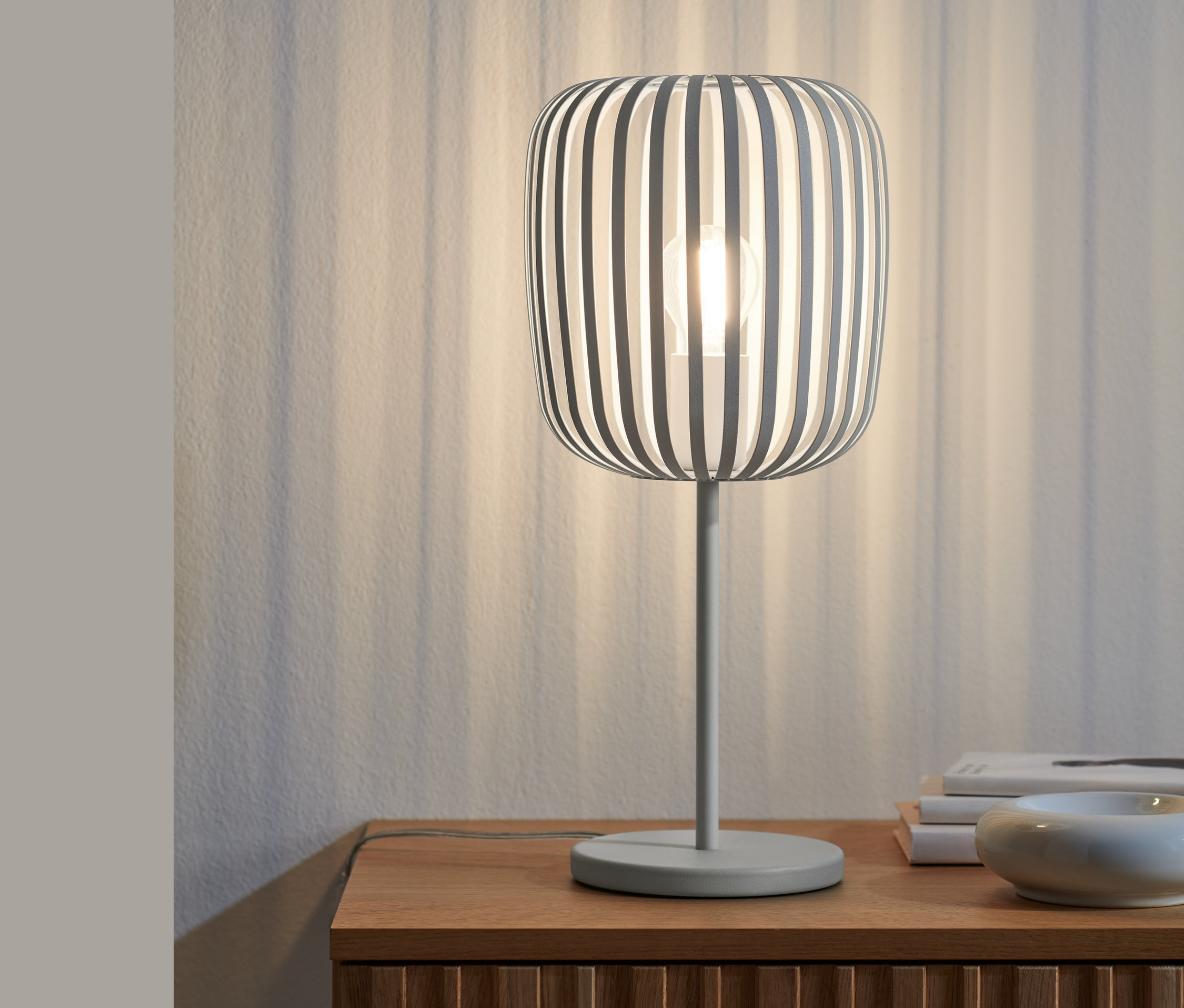 Eine Tischleuchte aus Metall steht auf einem Holzschrank.